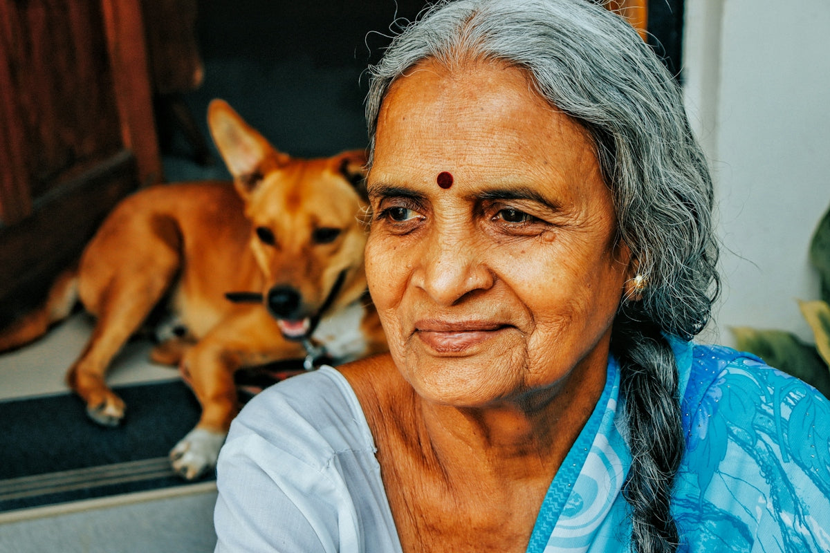 a woman sitting next to a dog on the ground